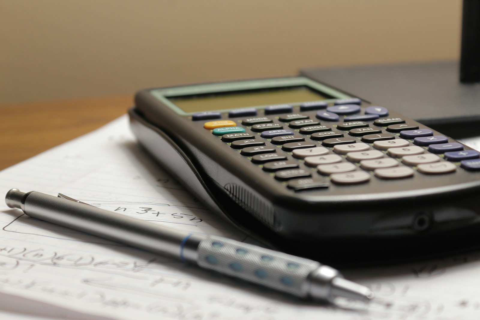 Una calculadora, una lapicera y unas notas sobre un escritorio