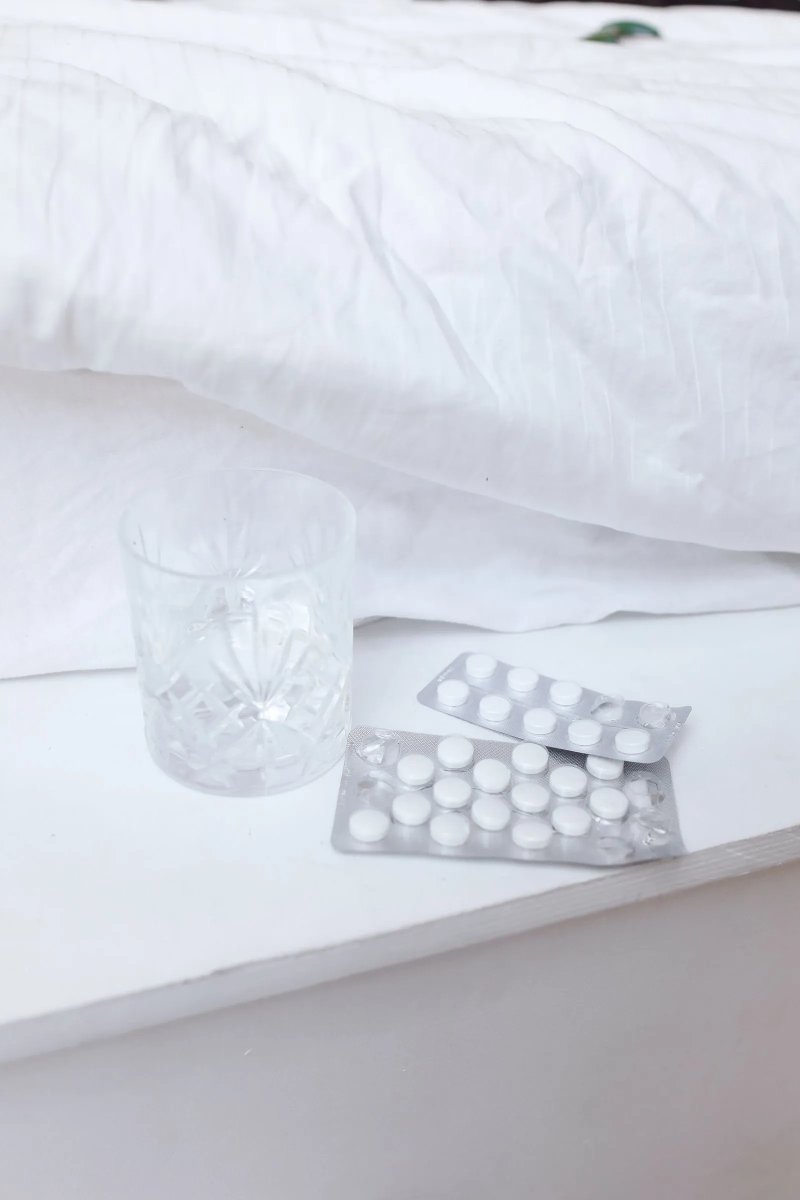 Stock photograph of tablet packs and a glass beside a bed. These are not the actual solengepras product.
