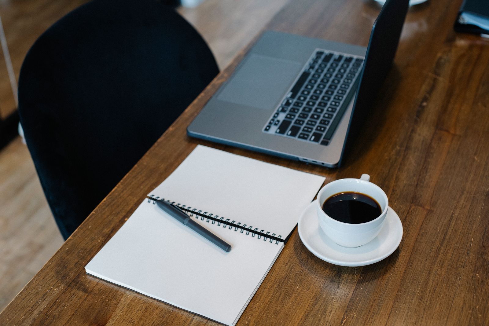An open laptop, notebook and pen on a table