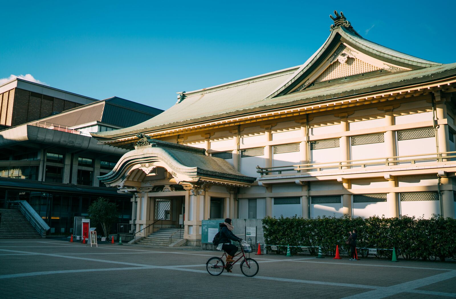 建物の前を自転車で通り過ぎる人