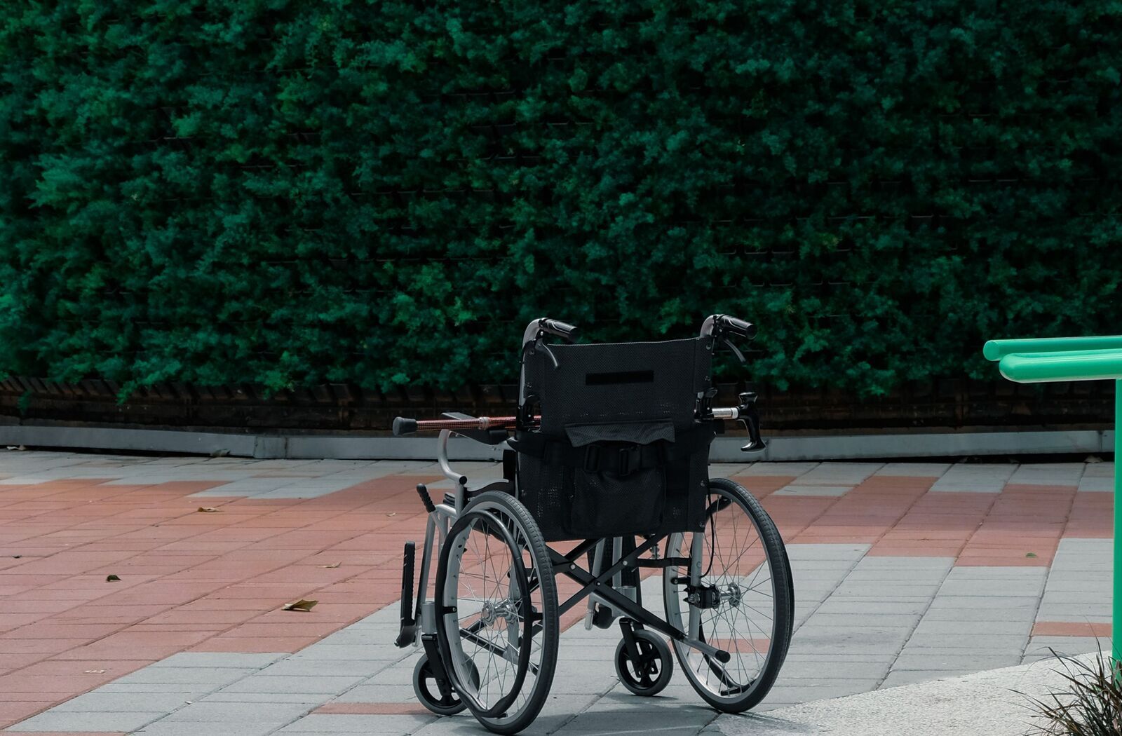 生垣の前に置かれた、杖を掛けた車椅子の後ろ姿